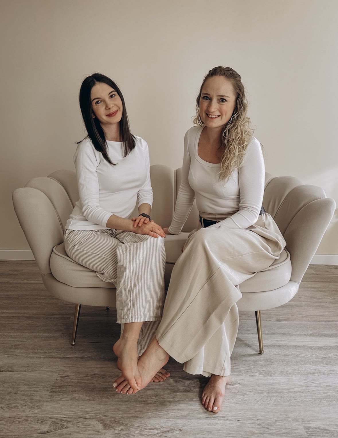 Julia und Viki sitzen entspannt nebeneinander auf hellen Muschelsesseln in der Praxis